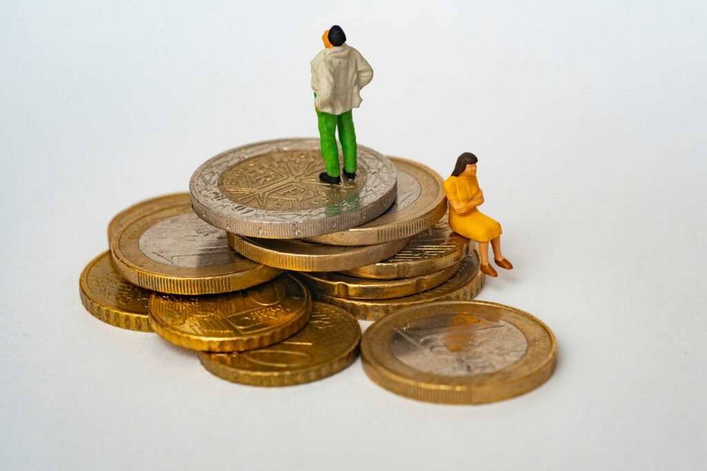 A miniature man and woman on a stack of gold and silver coins
